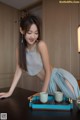 A woman in a blue dress sitting at a table with a cup of tea.