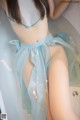 A woman in a blue lingerie sitting in a bathtub.