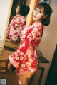 A woman in a red and white kimono standing in front of a mirror.