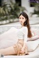 a woman sitting on top of a white couch next to a pool