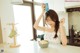 A woman sitting at a kitchen counter holding a box of cereal.