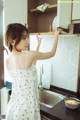 A woman in a white dress standing in a kitchen.