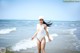 A woman in a white bathing suit standing in the ocean.