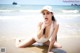 A woman in a white bathing suit sitting on the beach.