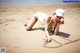 A woman laying on the beach writing in the sand.