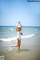 A woman in a white bathing suit standing in the ocean.