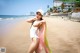 A woman in a white bathing suit and a white hat on a beach.