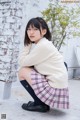 A young woman wearing glasses sitting on the ground.