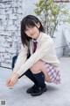 A young woman in a school uniform crouching on the ground.