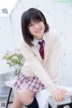 A young woman in a school uniform sitting on a chair.