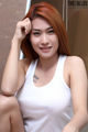 A woman in a white tank top posing for a picture.