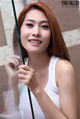 A woman in a white tank top holding a green pole.