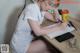 A woman sitting at a desk writing on a piece of paper.