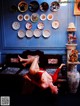 A woman laying on a couch in front of a wall of plates.