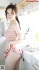 A woman in a pink dress standing in a kitchen.