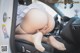 A woman in a white dress is sitting in a car.