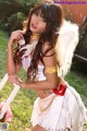 A woman dressed as an angel sitting on a bench.