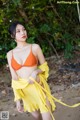 A woman in an orange bikini top and yellow skirt posing for a picture.