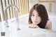 A young woman leaning on a kitchen counter next to a sink.