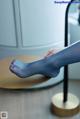 A woman's feet in blue tights sitting on a table.