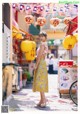 A woman standing in the middle of a street with yellow lanterns.