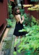 A woman in a black dress standing on a sidewalk.