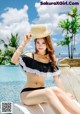 A woman in a black and white bikini sitting by a pool.