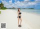 A woman in a black bikini standing on a beach.