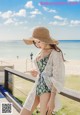 A woman in a bathing suit and hat on the beach.