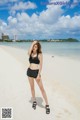 A woman in a black bikini standing on a beach.