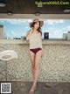 A woman in a bikini and hat standing on a balcony.