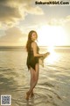 A woman in a black dress standing in the water.