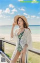 a woman in a bathing suit and hat standing on a beach