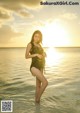 A woman in a black bathing suit standing in the ocean.