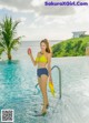 A woman in a yellow bikini standing in a swimming pool.