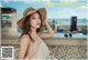 A woman wearing a straw hat sitting on a chair.