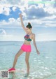 A woman in a bikini standing on a surfboard in the ocean.