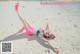 A woman in a pink bikini laying on the sand.