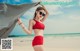 A woman in a red bikini standing on a beach.