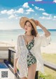 a woman in a bathing suit and hat on the beach