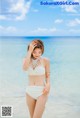 A woman in a white bikini standing on a beach.