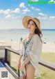 A woman in a bathing suit and hat standing on a beach.