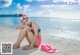 A woman in a bikini and goggles sitting on the beach.