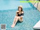 A woman sitting on the edge of a swimming pool.