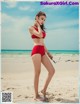 A woman in a red bikini standing on a beach.