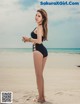 A woman in a black bathing suit standing on a beach.