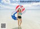 A woman in a bikini holding an inflatable ring in the ocean.