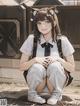 A girl in a school uniform sitting on the ground.