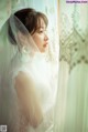 A woman in a wedding dress looking out of a window.