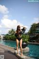 A woman in a black bathing suit standing next to a pool.